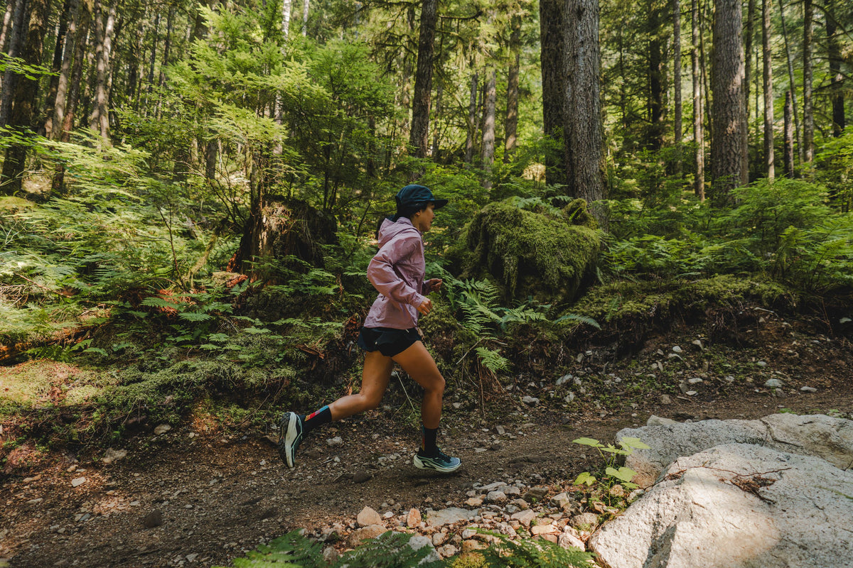 Runner in a pink jacket on a forest trail